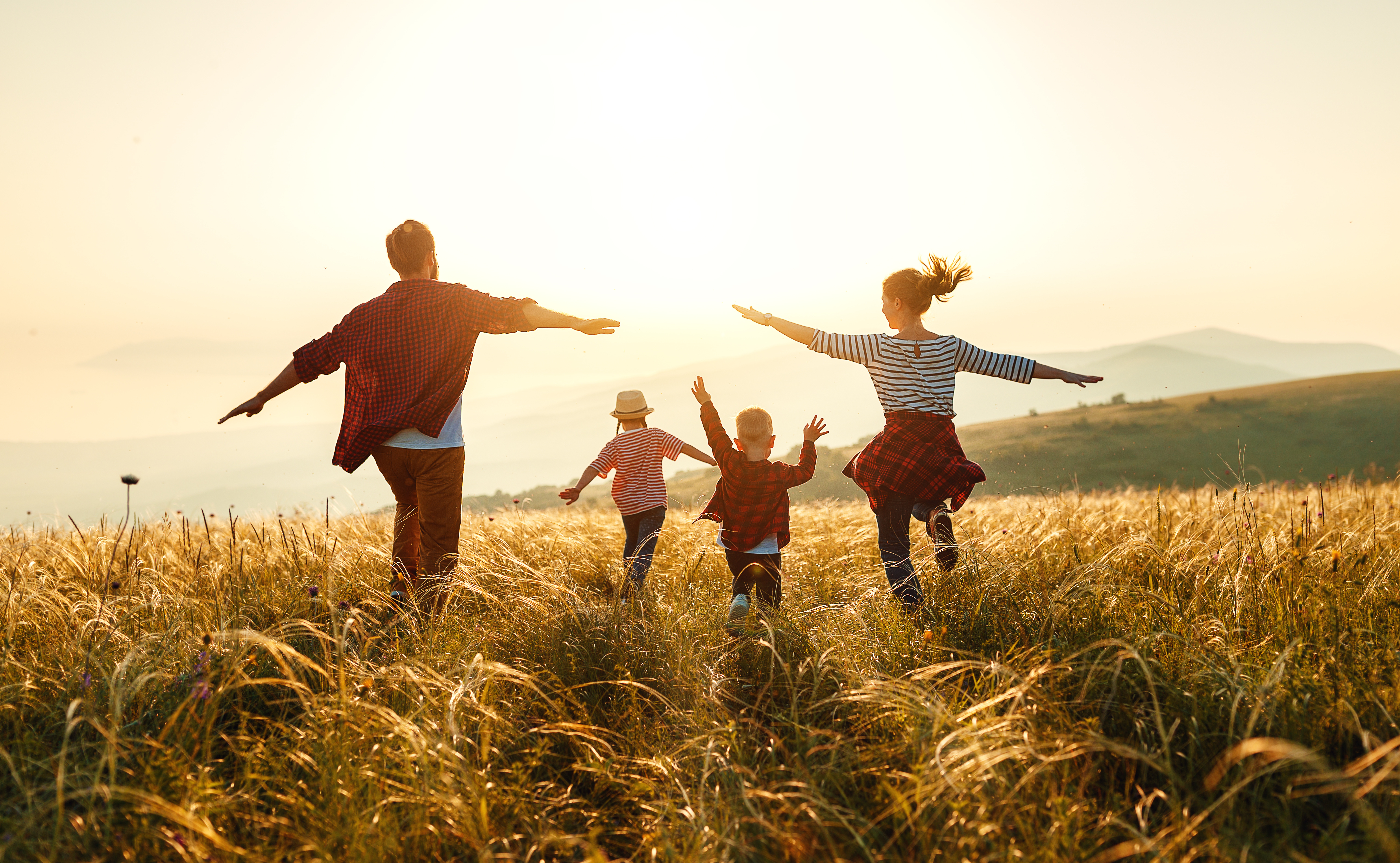 Familie läuft bei Sonnenuntergang durch ein Feld